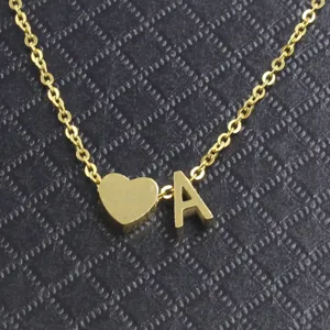 Close up detail view of gold tone stainless steel heart and alphabet letter pendant necklace.