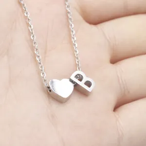 Detail shot of a silver stainless steel heart and letter B pendant necklace on hand.