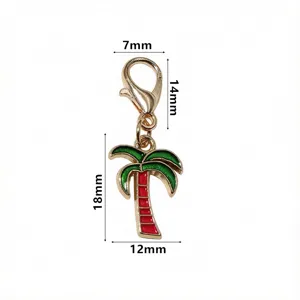 Détail en gros plan du pendentif palmier en alliage doré avec tronc rouge et feuilles émaillées.