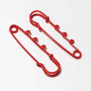 Detailed view of red metal safety pin charms with hanging loops, diy hardware accessory.
