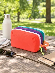 Detail view of the colorful multi-layer travel cosmetic bag on outdoor wooden table.