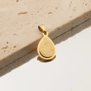 Gros plan du pendentif goutte d'or, montrant la texture givrée délicate et son anneau.