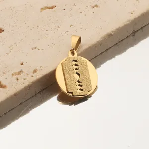 Gros plan détaillé du pendentif rond plaqué or 18K avec un motif de lame de rasoir givrée.