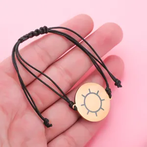 Minimalist black braided cord bracelet with gold sun disc pendant for daily wear and fashion style.