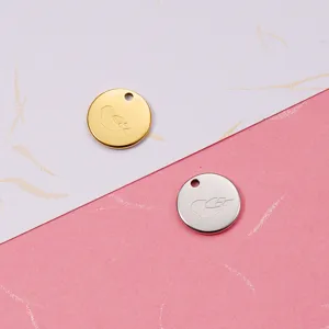 Close up detail of round mirror polished stainless steel DIY bird engraved charm pendants.