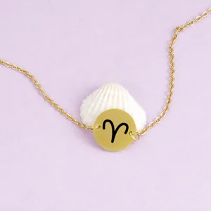 Detail shot of gold stainless steel chain bracelet with Aries zodiac sign pendant on shell.