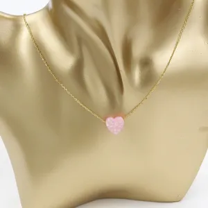 Close-up detail of the pink heart opal pendant on a dainty gold stainless steel chain necklace.