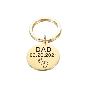 Close-up of polished stainless steel round keychain with engraved dad and baby footprints.