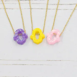 Resin hamsa hand pendant necklace set in purple yellow pink with gold chain details.