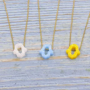Detail view of three resin Hamsa hand pendant necklaces featuring gold stainless steel chains.