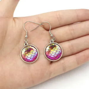 Detailed close-up of fish scale earrings with resin and steel hooks, vibrant pink shimmer.