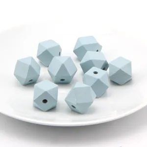 Close-up detail view of light blue multifaceted wooden beads on white plate for DIY crafts.