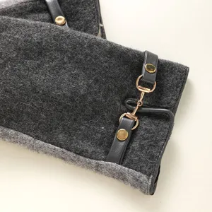 Detail view of grey wool blend winter gloves featuring black leather strap and golden horsebit.