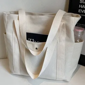 Detail view of the beige canvas tote bag with front pocket and double straps for daily commute.