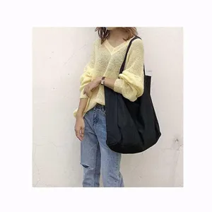 Detail view of the large capacity black canvas shoulder bag worn by model in daily outfit style.