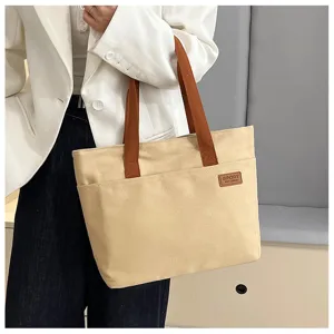 Detail close-up view of casual beige canvas tote bag featuring brown straps and pocket.