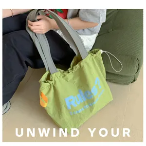 Green canvas tote bag detail view showing comfortable shoulder straps and drawstring design.