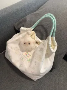 Detailed shot of a cute canvas tote bag with rabbit print, plush charm, and green handles.