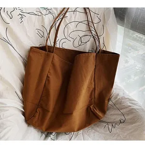 Brown canvas shoulder bag detail shot, simple large capacity design for daily use.