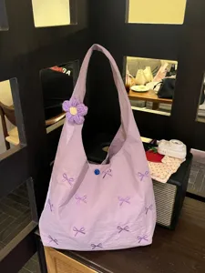 Purple canvas shoulder bag featuring cute embroidered bows and a matching crochet flower charm.