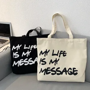 Detailed view of casual canvas tote bags in black and off-white with inspiring letter print.