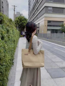 Outdoor street scene showing canvas tote bag details, shoulder wear view and large capacity.