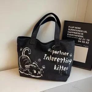 Black canvas tote bag detail view, featuring cute cat graphic and letter print, daily casual style.