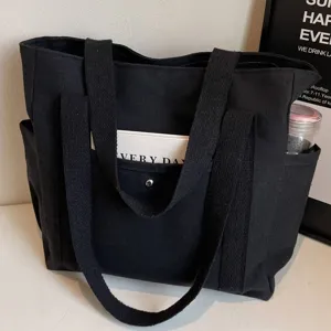 Black canvas tote bag detail showing large capacity, dual straps and side pockets.