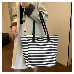 Detail view of a black and white striped canvas tote bag, featuring large capacity and dual handles.