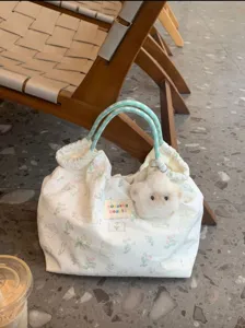 Close-up detail of the cute canvas tote bag with rabbit print, green handles and plush charm.