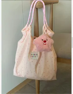 Cute pink rabbit print canvas tote bag detail, featuring checkered straps and plush star charm.