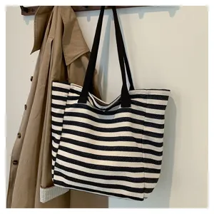 Detailed view of the casual black and white striped canvas tote bag hanging on wall hook.