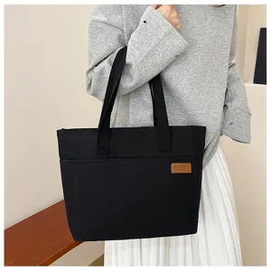 Detail view of the black canvas tote bag showing the textured fabric and sturdy handles.