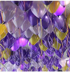 Vue détaillée de ballons de fête colorés violet, or et argent avec des rubans suspendus.