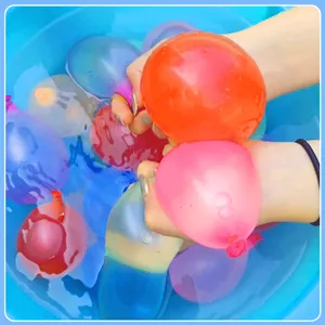 Detailed view of colorful water balloons filling in a blue bucket for summer outdoor fun.