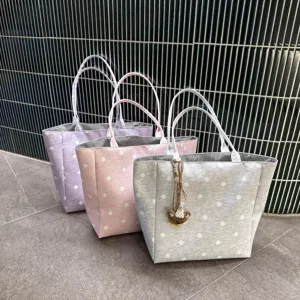 Detail shot of stylish large capacity polka dot canvas tote bags in purple, pink, and grey.