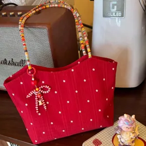 Detailed view of red floral canvas tote bag, colorful beaded straps, cute bow pendant.