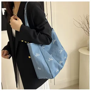 Stylish blue denim canvas tote bag for women with white bow patterns, ideal casual shoulder bag.