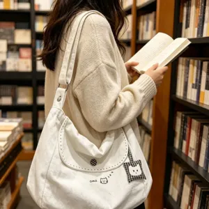 Large capacity white canvas shoulder bag with cute cat embroidery and minimalist style.