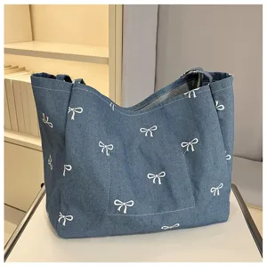 Detailed view of casual blue denim tote bag with cute white bow print and large capacity.