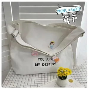 Canvas tote bag detail view showcasing cute decorative badges and printed lettering details.