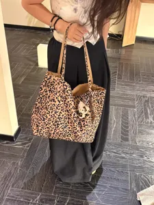 Detailed view of a stylish leopard print canvas tote bag with a cute plush pendant accessory.