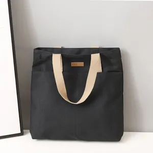 Detailed view of the black canvas tote bag with sturdy handles, daily casual commuter bag.