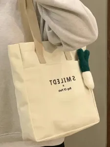 Canvas tote bag for women casual large capacity shoulder bag with cute plush pendant detail.