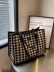 Détail du sac cabas en toile à carreaux noir et blanc avec poignées solides et étiquette.