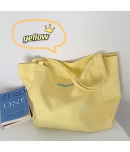 Canvas tote bag detail view, casual yellow shoulder bag with lettering, minimalist aesthetic.