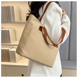 Vue détaillée d'un sac cabas en toile beige avec des anses marron pour un usage quotidien.