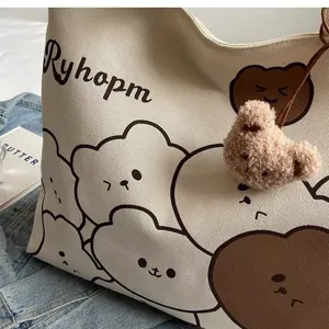Cute cartoon bear canvas tote bag detail close-up showing soft fabric texture and fuzzy pendant.