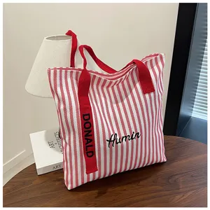 Red and white striped canvas tote bag detail showing embroidered Humin and Donald text.