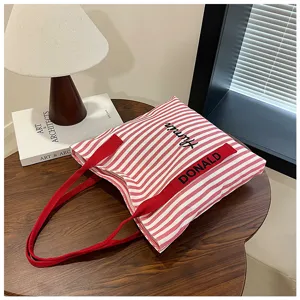 Red and white striped canvas tote bag featuring top handles and stylish embroidery.